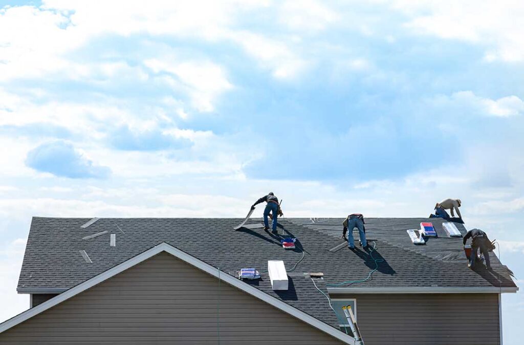 Separated asphalt shingles, metal flashing, and roofing debris in covered bins beside a residential work site.