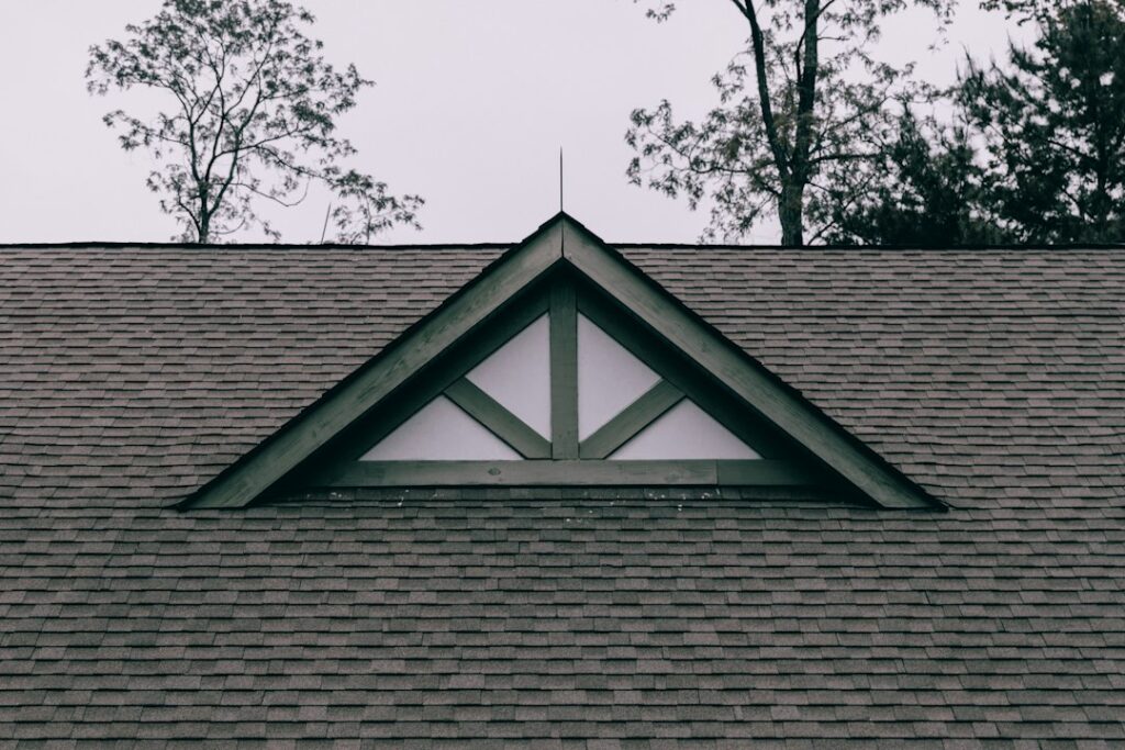 A residential house with a gable roof, dormer windows, broad eaves, and visible attic ventilation details