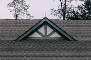 A residential house with a gable roof, dormer windows, broad eaves, and visible attic ventilation details