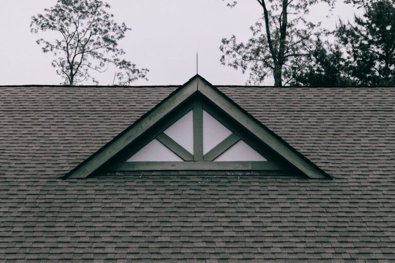 A residential house with a gable roof, dormer windows, broad eaves, and visible attic ventilation details